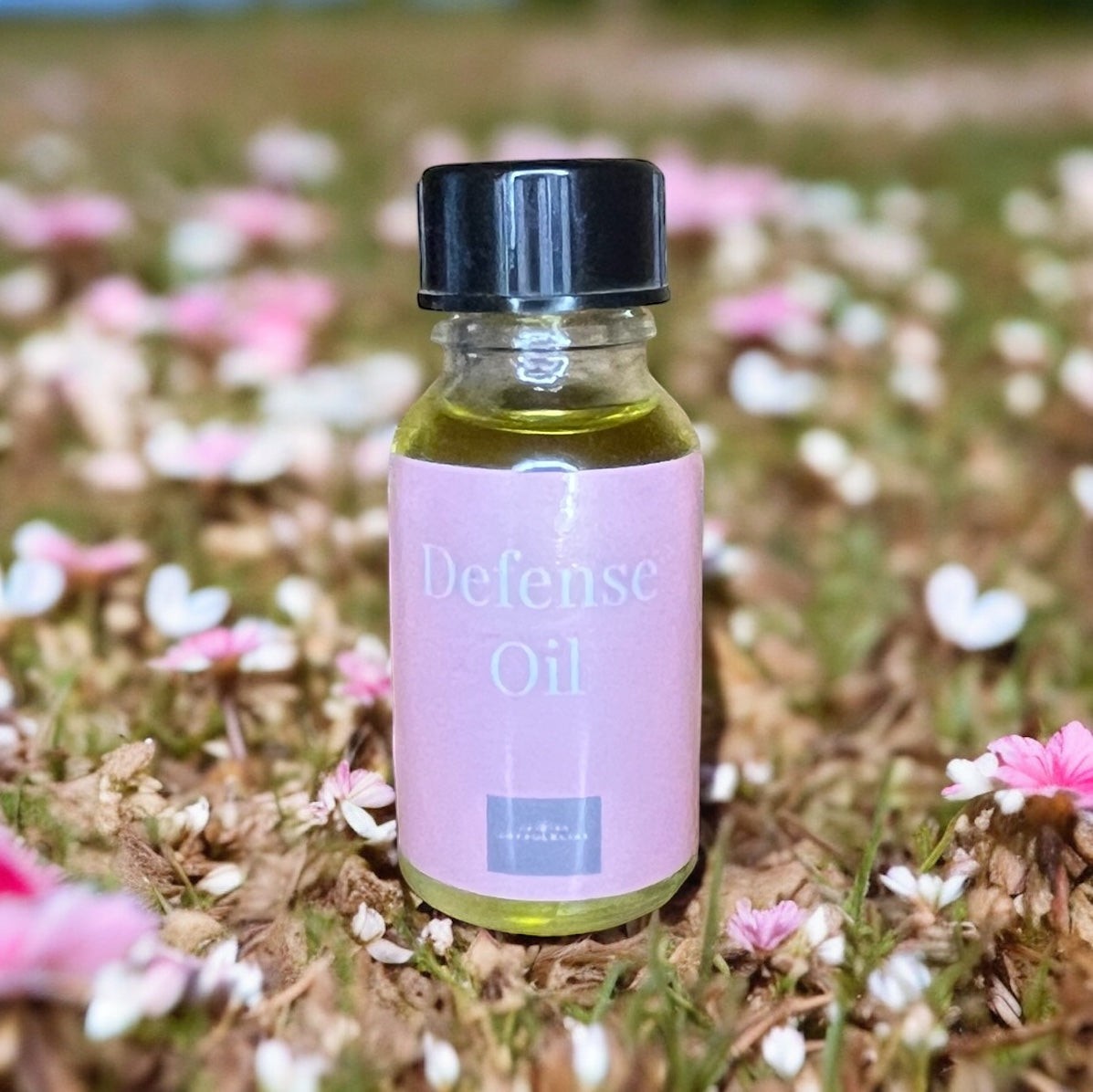 JoyfulBliss Co. Defense Ritual Anointing Oil in a 10ml glass bottle with a pink label, set against a floral background.