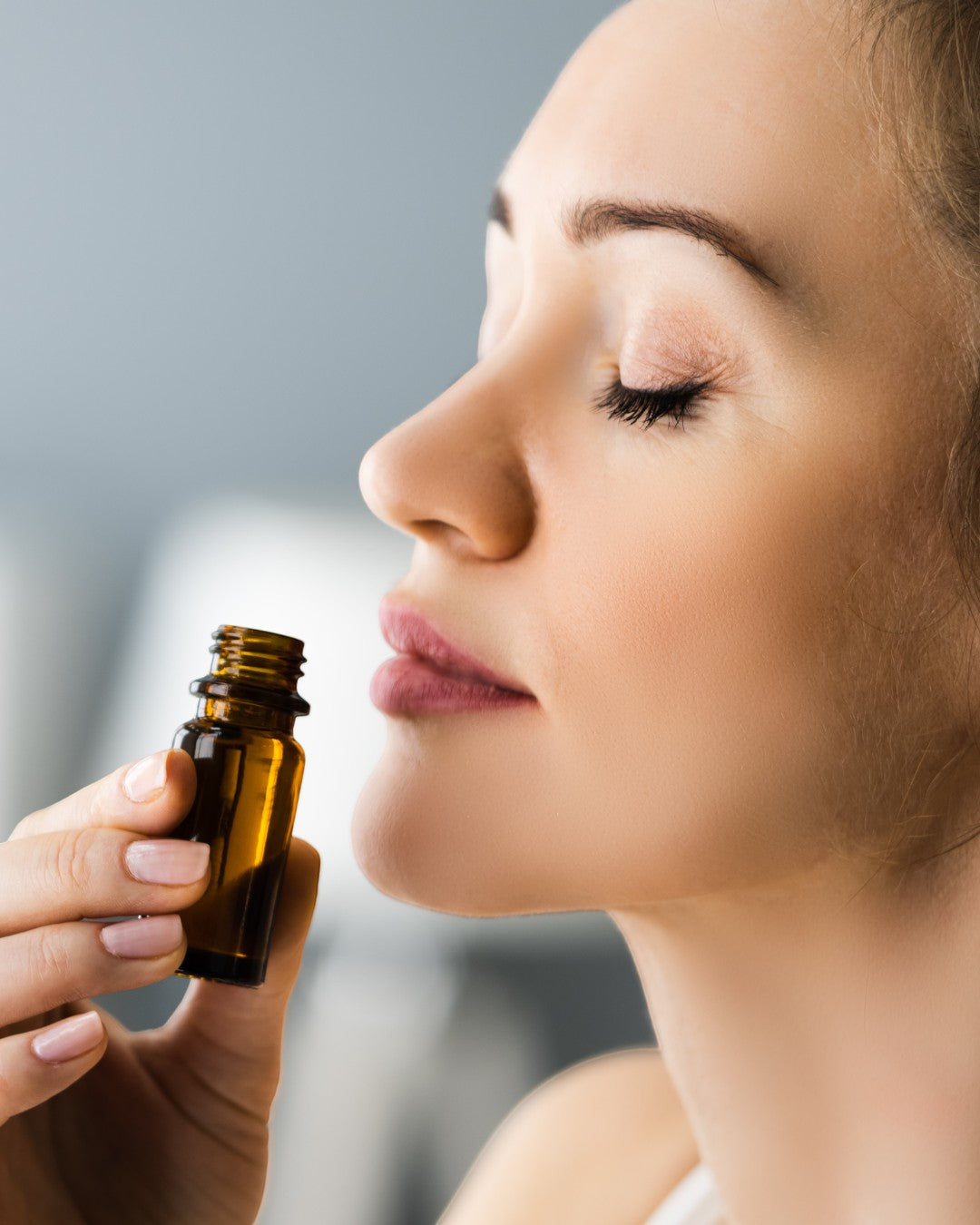 Woman smelling JoyfulBliss Co. Defense Ritual Anointing Oil from a small amber glass bottle for spiritual protection