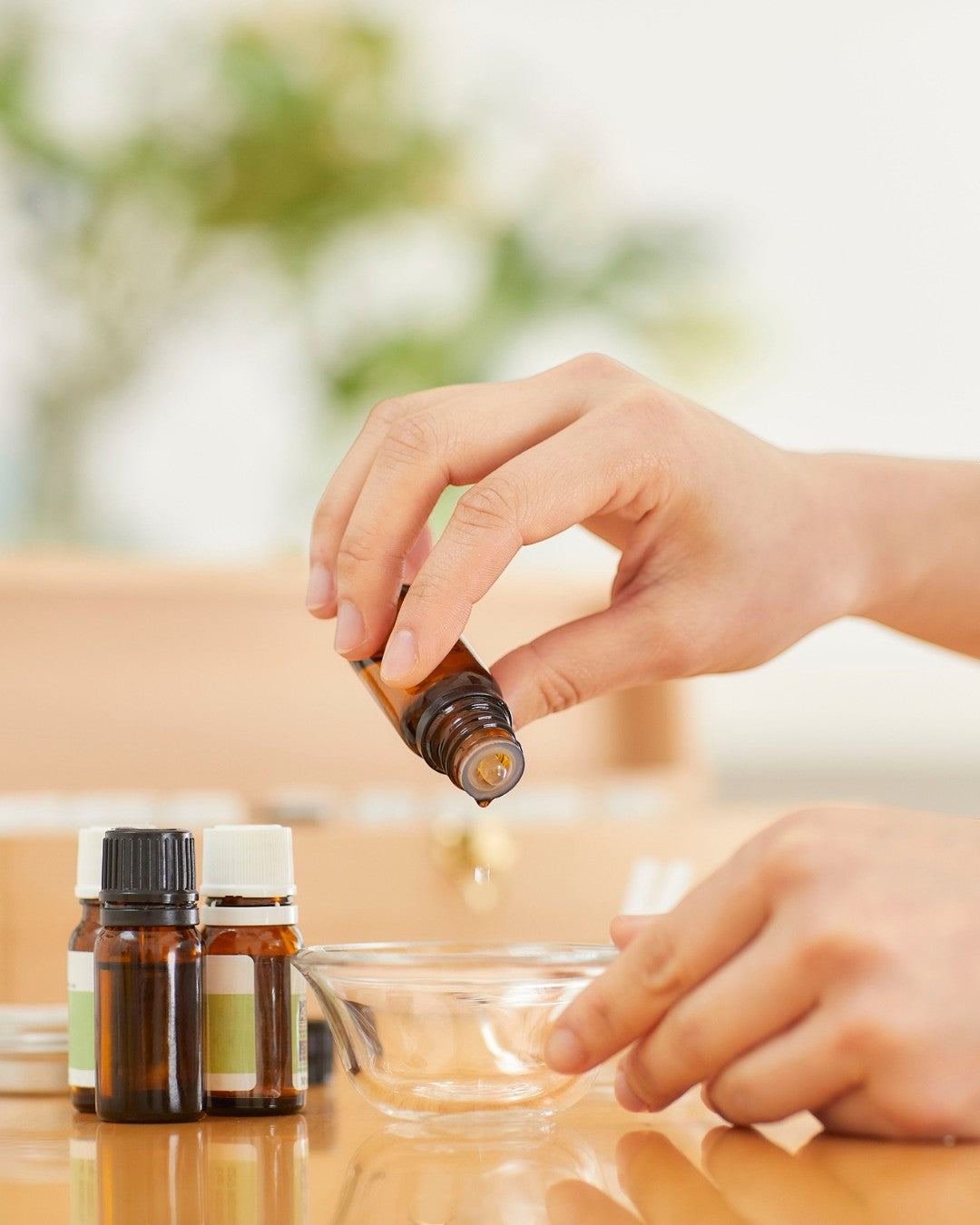 JoyfulBliss Co. Defense Ritual Anointing Oil being poured from a small amber glass bottle into a clear glass bowl.