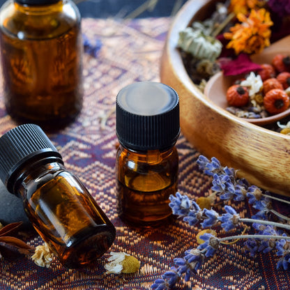 JoyfulBliss Co. Defense Ritual Anointing Oil in amber glass bottles with dried lavender and herbs on a patterned cloth.