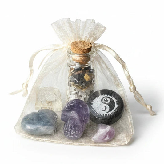 JoyfulBliss Co. Protect + Deflect Mojo Bag with crystals, spell jar, and yin-yang charm in a white organza pouch.
