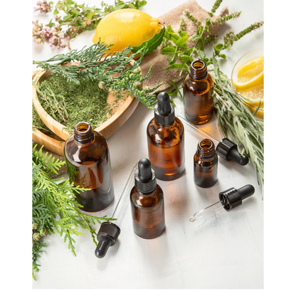 JoyfulBliss Co. ritual anointing oil in amber glass dropper bottles surrounded by fresh lemon, herbs, and greenery.