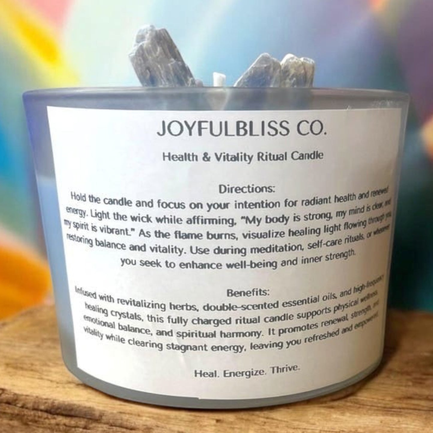 JoyfulBliss Co. Heal + Vitalize ritual soy candle in a glass jar topped with healing crystals on a wooden surface.